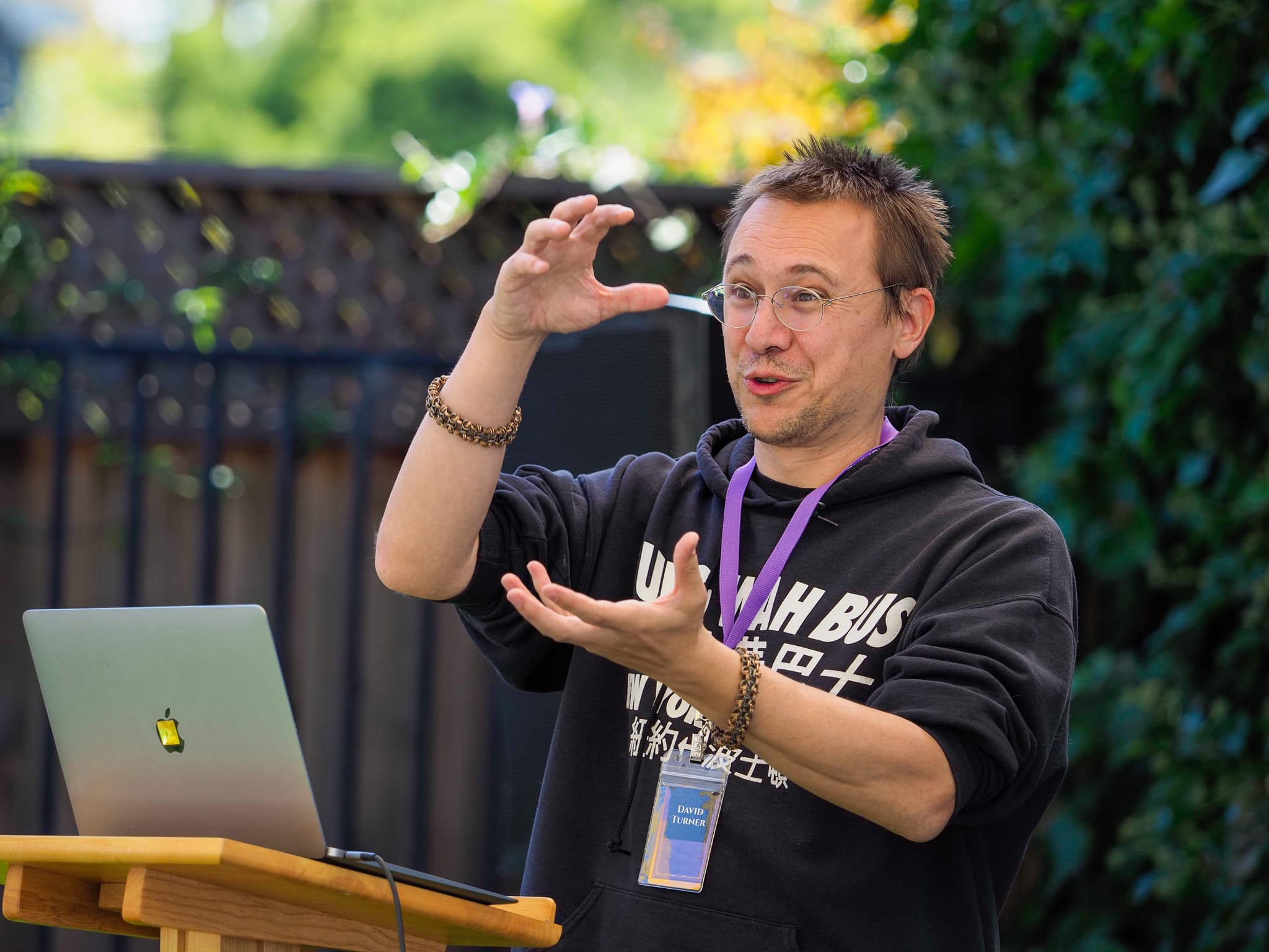 David Turner presenting from a lectern in the Lighthaven garden